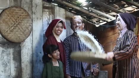 A-happy-Javanese-family-with-their-two-children-with-a-tray-of-rice-at-kitchen,-Central-Java,-Indonesia