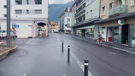 Couple-Talking-As-Car-Passes-|-Interlaken-Switzerland-Immersive-Travel-Tourism-Mountainside-Valley-Resort-City,-Europe,-Walking,-Rainy-Day,-4K
