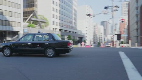 Un-Taxi-Japonés-Circulando-Por-Una-Intersección-En-Tokio,-Japón,-En-Un-Día-Soleado.