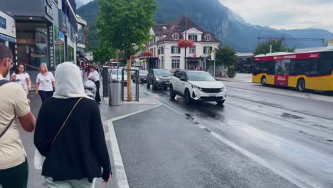 Travelers-With-Luggage-Near-Heavy-Traffic-|-Interlaken-Switzerland-Immersive-Travel-Tourism-Mountainside-Valley-Resort-City,-Europe,-Walking,-Rainy-Day,-4K