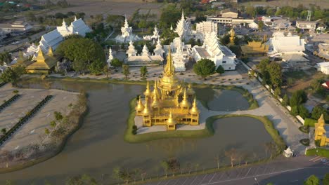 Aerial-drone-of-Wat-Rong-Khun-the-giant-buddhist-White-Temple-and-Golden-Temple-with-mountains-and-landscape-in-Chiang-Rai,-Thailand