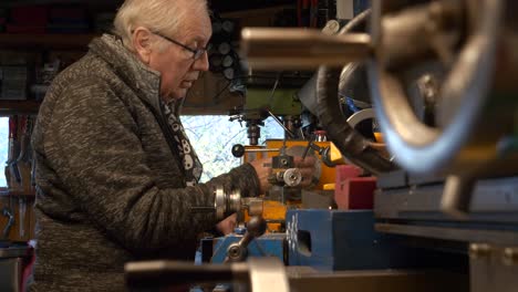 Mature-man-mechanical-engineer-setting-up-a-lathe-machine-in-workshop