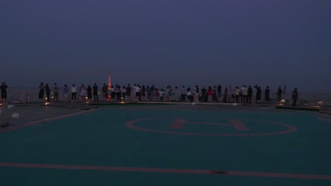 Ein-Hubschrauberlandeplatz-Mit-Dunkler-Kamera-Am-Mori-Tower-Mit-Touristen-Im-Hintergrund