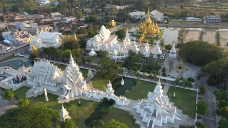 Aerial-drone-of-Wat-Rong-Khun-the-big-buddhist-White-Temple-and-Golden-Temple-with-mountains-and-landscape-in-Chiang-Rai,-Thailand