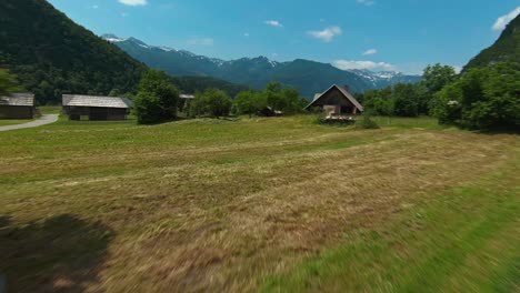 Volando-Sobre-Tierras-De-Cultivo-Y-Casas-De-Madera-En-El-Pueblo-De-Montaña-Cerca-Del-Lago-Bohinj,-Eslovenia