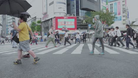 People-walking-over-the-Shibuya-Crossing-in-Tokyo,-Japan-while-its-raining
