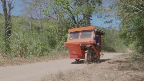 Ein-Rotes-Dreirad,-Das-Auf-Den-Philippinen-Eine-Unbefestigte-Straße-Hinunterfährt