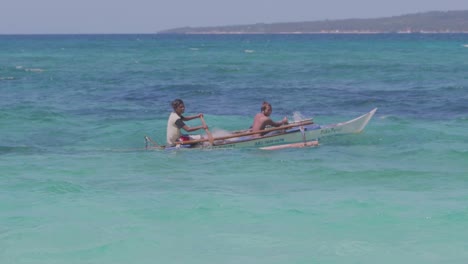 two-young-men-paddling-in-a-small-boat-over-the-pacific-ocean-in-the-philippines