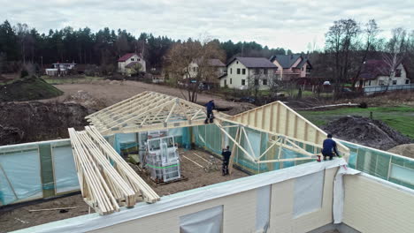 Construction-workers-installing-wooden-beams-and-trusses-on-house-roof