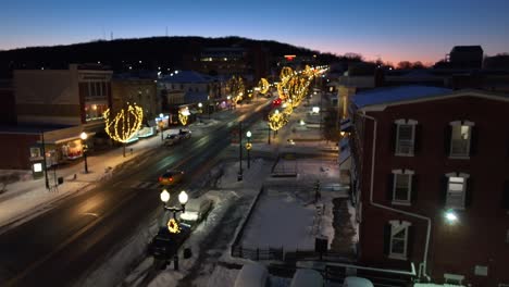 Snowy-American-town-Main-Street-decorated-with-festive-Christmas-lights-and-USA-flag