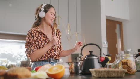 Girl-with-headphones-in-kitchen-sings-along-to-favorite-song-using-wooden-spoon