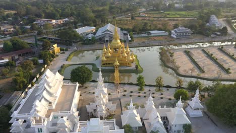 Luftdrohne-Von-Wat-Rong-Khun,-Dem-Riesigen-Buddhistischen-Weißen-Tempel-Und-Dem-Goldenen-Tempel-Mit-Bergen-Und-Malerischer-Landschaft-In-Chiang-Rai,-Thailand