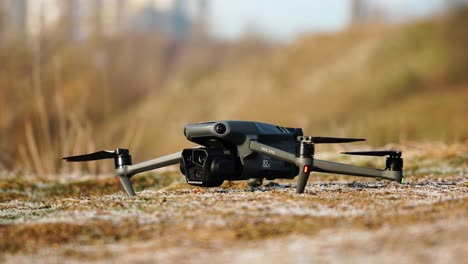 Turned-on-drone-ready-for-take-off-on-yellow-countryside-gravel-ground