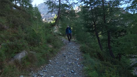 Slow-motion-front-shot-of-man-approaching-camera-in-nature-trail-path,-Valmalenco