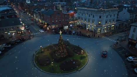Snowflakes-falling-on-small-historic-town-in-USA-with-Christmas-tree-and-decorations-at-night