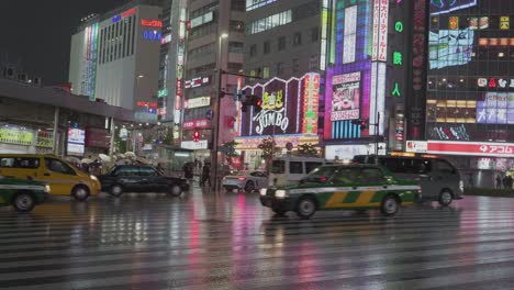 Una-Enorme-Intersección-De-Tráfico-En-El-Distrito-De-Shinjuku,-Tokio,-Japón,-En-Una-Noche-Lluviosa