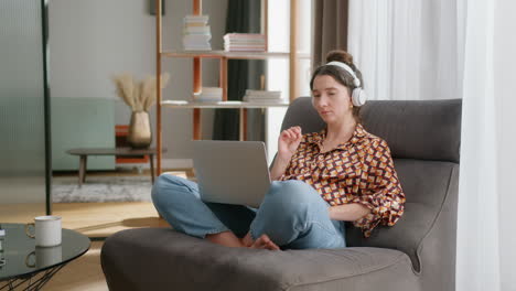 Caucasian-lady-wearing-wireless-headphones-get-online-instruction-using-laptop