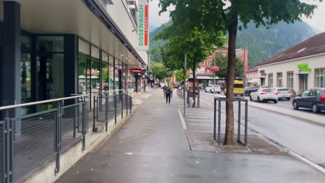 People-Walking-Downtown-on-Sidewalk-|-Interlaken-Switzerland-Immersive-Travel-Tourism-Mountainside-Valley-Resort-City,-Europe,-Walking,-Rainy-Day,-4K