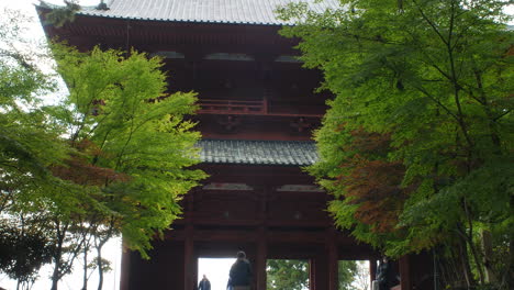 Tourists-Seen-Walking-Towards-Imposing-Koyasan-Daimon-Gate-With-Trees-On-Either-Side