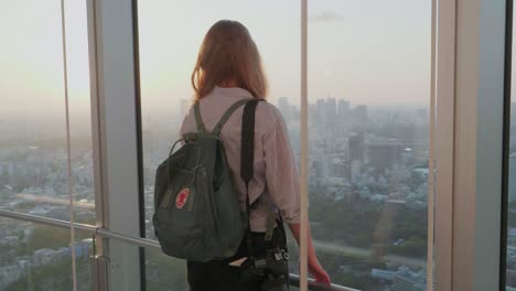a-western-tourist-standing-in-front-of-the-Tokyo-Skyline-while-sunset-enjoying-the-view