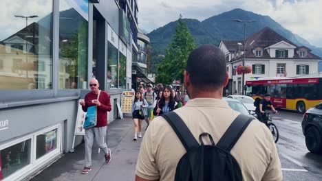 Couple-Walking-Along-Busy-Streets-In-City-|-Interlaken-Switzerland-Immersive-Travel-Tourism-Mountainside-Valley-Resort-City,-Europe,-Walking,-Rainy-Day,-4K