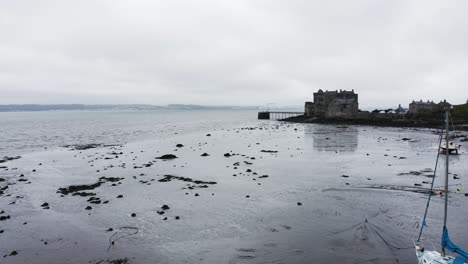 Beached-sailboats-at-low-tide-sitting-in-front-of-Blackness-Castle-in-Scotland