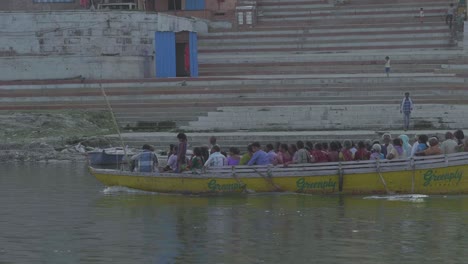 Ein-Gelbes-Boot-Voller-Touristen-Auf-Dem-Ganga-Fluss-In-Den-Berühmten-Varanasi-Ghats-In-Indien