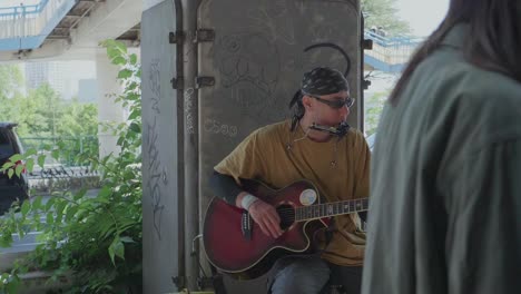 Ein-Straßenmusiker-In-Tokio-Spielt-An-Einem-Sonnigen-Tag-Gitarre,-Während-Viele-Menschen-Vorbeigehen