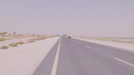 Green-Sports-Car-Racing-through-the-Desert-in-Dubai,-United-Arab-Emirates