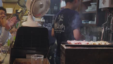 Un-Chef-Preparando-Comida-Deliciosa-En-El-Famoso-Callejón-De-Omoide-Yokocho-En-Shinjuku-Tokio,-Japón