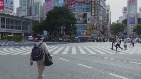 Thousands-of-People-walking-over-the-world-famous-Shibuya-Crossing,-which-is-the-busiest-intersection-in-the-world,-on-a-beautiful-sunny-day-in-slow-motion