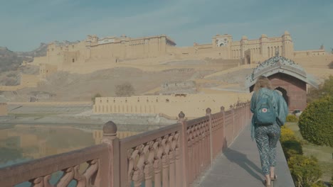 a-blonde-female-tourist-walking-in-front-of-the-world-famous-Amber-Fort-in-Jaipur,-Rajasthan-India