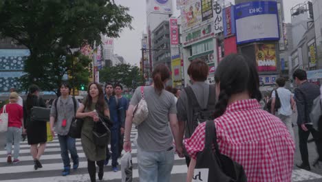 Zeitlupenperspektive-Beim-Überqueren-Der-Straße-In-Shibuya-An-Einer-Belebten,-Berühmten-Kreuzung,-Umgeben-Von-Werbung