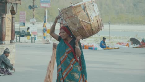 Una-Mujer-India-Que-Lleva-Un-Enorme-Cubo-Lleno-De-Cosas-Que-Muestran-El-Papel-De-La-Mujer-En-La-Ciudad-India