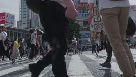 Thousands-of-People-walking-over-the-world-famous-Shibuya-Crossing,-which-is-the-busiest-intersection-in-the-world,-on-a-beautiful-sunny-day-in-slow-motion