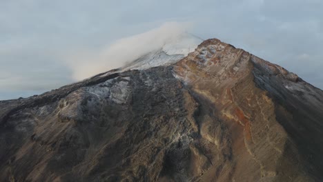 Panoramic-aerial-view-of-a-high-mountain-with-a-glacier-and-clouds-on-the-summit