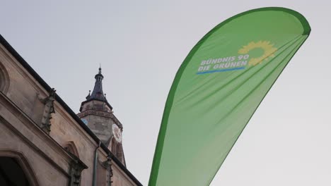 Flag-Of-The-Political-Party-Bündnis-90-Die-Grünen-In-Front-Of-A-Church-In-Tübingen,-Germany