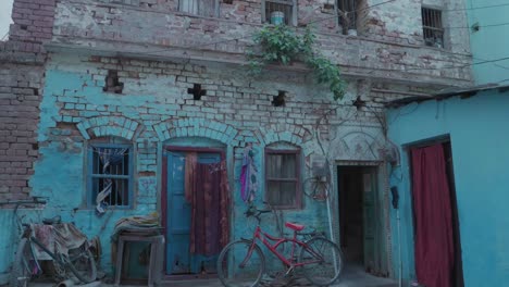 Dos-Niñas-Indias-Caminando-Frente-A-Una-Casa-Azul-En-Jodhpur,-India