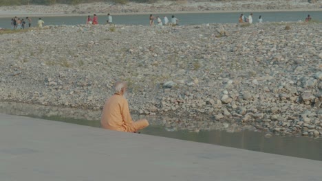 a-lonely-indian-guru-praying-at-the-ganga-river-on-a-very-hot-day-in-Rishikesh,-India