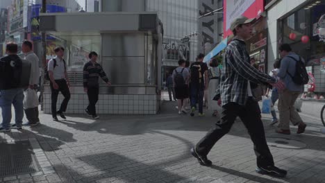 many-people-walking-along-a-sidewalk-in-Shibuya,-Tokyo-in-Japan-on-a-sunny-day