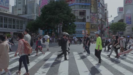 People-walk-over-the-world-famouss-crossing-Shibuya-in-Tokyo,-Japan-on-an-overcast-sunny-day