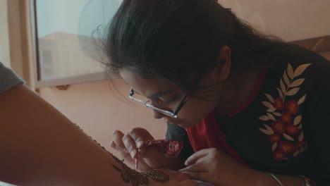 Eine-Indische-Frau-Kreiert-Ein-Traditionelles-Henna-Tattoo-Auf-Der-Hand-Einer-Touristin-In-Jaipur,-Indien