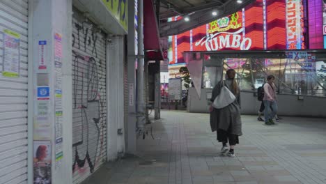 Una-Mujer-Solitaria-Caminando-Por-Las-Calles-De-Shinjuku-En-Tokio,-Japón,-Por-La-Noche.