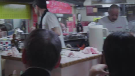 Kamera-Geht-Nachts-Durch-Die-Berühmte-Omoide-Yokocho-Gasse-In-Tokio,-Japan,-Mit-Vielen-Menschen,-Die-Essen-Und-Trinken