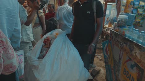 Indian-Girl-Carrying-A-Large-Bag-Through-An-Market-Place-Full-Of-Rubbish