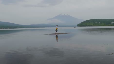 Young-male-walking-on-sandbank-in-front-of-Mount-Fuji-volcano