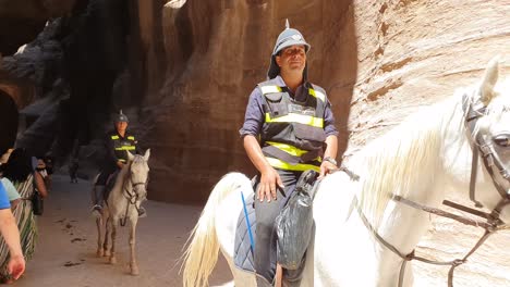 Touristen-Rücken-Der-Verkehrspolizei-Auf-Pferden-Zur-Seite,-Während-Sie-In-Den-Durchgängen-Von-Petra-In-Jordanien-Vorbeireiten