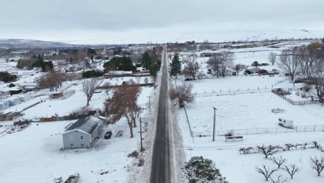 Drone-shot-of-a-plowed-road-cutting-through-the-snow-filled-rural-countryside