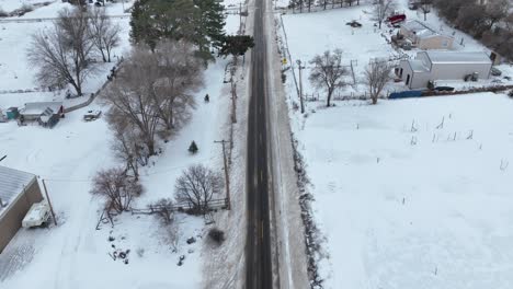 Aerial-shot-of-a-plowed-road-cutting-through-rural-farmland-with-snow-covering-the-land