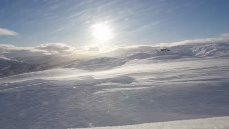 Dynamische-Winterszene-Mit-Klarem-Himmel-Und-Sonne,-Schneewirbel-Im-Vordergrund,-Norwegen